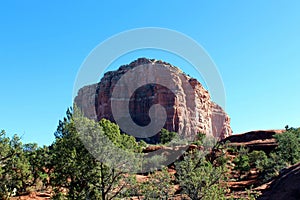 The Bell Rock sandstone formation surrounded by Cypress tress in Sedona, Arizona, USA