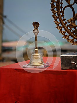 Of a bell on a table wrap  with red cloth and Brass made statue of Lord Natraj with water droplets.