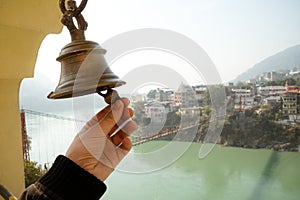 Bell in Tera Manzil Temple. Rishikesh. India. ringing of the bell in the temple. the hand holds the bell photo