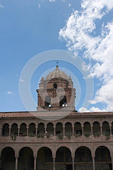 A bell tower atop a two story stone wall lined with columns and arches at the Belmond Monasterio Hotel in Cusco, Peru photo