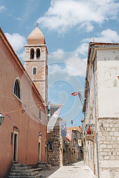 Bell tower of the Church of St. Justine and narrow street of old town of Rab on the island Rab, Croatia