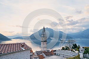 Bell tower of the Church of St. Nicholas over the roofs of old houses against the backdrop of the mountains in the