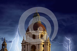 The bell tower on the city hall buildings covered in red brick with storm clouds and lightning in Pasadena California