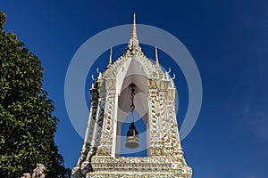 Bell tower, Wat Po, Bangkok. White tower, single bell. Blue sky in background. photo
