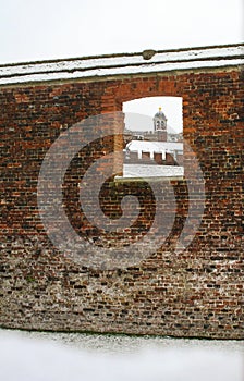 Bell tower at Hampton Court Palace through a wall after a snowfall