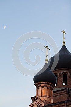 Bell tower of old believer orthodox church at early winter morning, crosses with moon in the sky