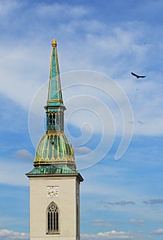 Bell tower of an old church with a flying bird against blue sky