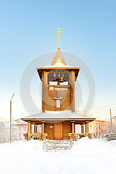 Bell tower wooden church of logs in winter on a sunny day