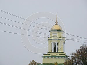 Bell tower of the yellow church on the autumn sky background