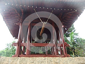 Bell, trees, wooden structure in brown color in the style of architecture in a Buddhist temple