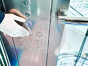 Bellboy hand wearing rubber glove to press the button on the elevator. New normal lifestyle after Coronavirus, Touchless society