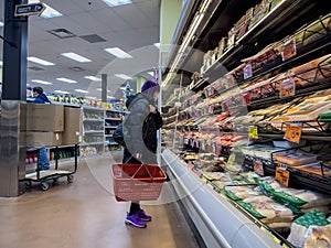 Bellevue, WA USA - circa December 2022: Wide view of people shopping in the refrigerated food section of a Trader Joes grocery