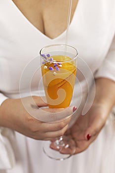 Bellini with prosecco and a peach outdoors. Woman holding a glass outdoors