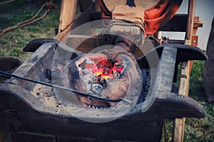 The bellows of the blacksmith fanning the fire in the coals. Evening work at the old forge