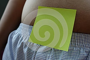 Belly of a fat man with green post note paper sticker