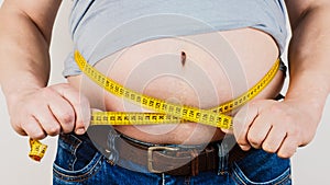 The belly of a fat man isolated on white background. Fat man holding a measuring tape. Weight Loss.
