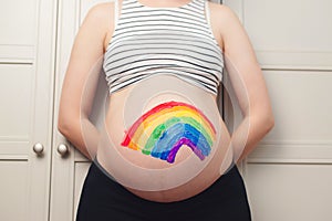 Belly painting, rainbow. Pregnant woman holding belly with painting. Waiting for baby concept. Belly painting and maternity photo