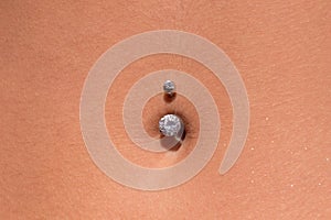 Belly piercing in the navel close up
