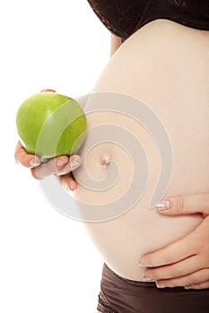 Belly of a pregnant woman with green apple