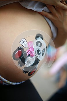 Belly of a pregnant woman on a light background