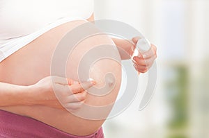 Belly of pregnant woman and moisturizing cream