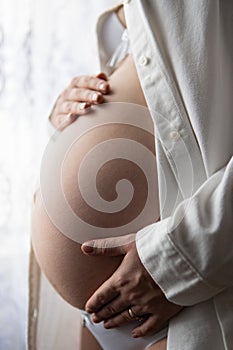 Belly of pregnant woman over white background, Image of pregnant woman touching her belly with hands, nine month.