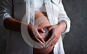 Belly of a pregnant woman. Pregnancy concept. Woman holding hands in heart shape