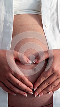 Belly of a pregnant woman. Pregnancy concept. Woman holding hands in heart shape