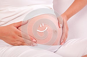 Belly of pregnant woman with smile symbol