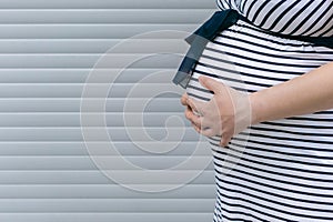 Belly of pregnant woman in in striped background