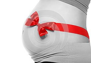 Belly of a pregnant woman tied with a red bow