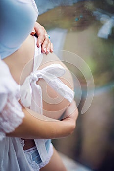 Belly of pregnant woman in white dress