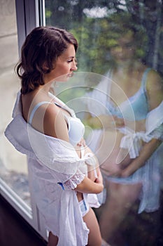 Belly of pregnant woman in white dress