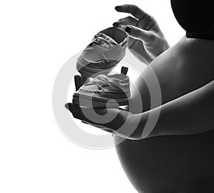 Belly of young pregnant bump woman standing with small baby boot