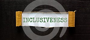 Belonging and inclusiveness symbol. The word `inclusiveness` appearing behind torn black paper. Beautiful black background. photo