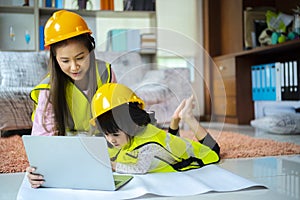 A beloved Asian mother and daughter pretend to be an engineer and smile with a safety hat in the house