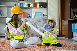 A beloved Asian mother and daughter pretend to be an engineer and smile with a safety hat in the house