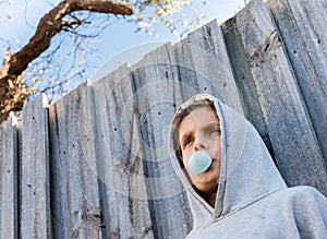 Below angled view of teenage boy blowing blue bubble gum