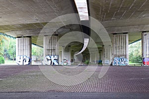 Below a curved highway overpass with graffiti photo