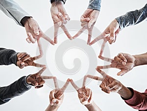 Below hands in circle making a star shape. A group of people putting their fingers together while standing in a huddle