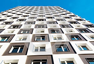 Modern and new apartment building. Photo of a tall block of flats against a blue sky.