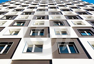 Modern and new apartment building. Photo of a tall block of flats with balconies against a blue sky.