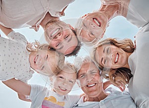 Below shot of multi-generation family smiling in a huddle against the blue sky. Carefree family with two children