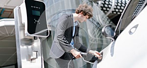 Below view closeup progressive black suit businessman recharge battery of EV car