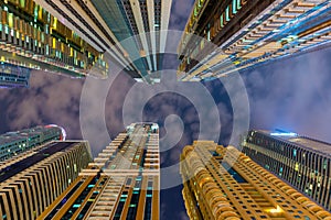 Below view on the luxury modern skyscrapers in Dubai Marina, shot at cloudy night.