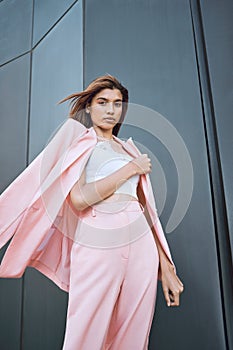 Below view portrait of young beautiful mixed race woman standing alone in a city and posing in fashionable clothes