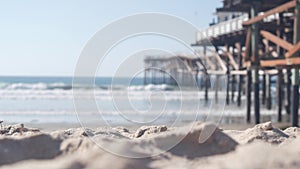 Below wooden Crystal pier on piles, ocean beach water waves, California USA.