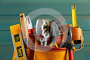 Belt with different tools on light blue wooden background, closeup