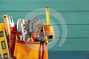 Belt with different tools on light blue wooden background. Space for text