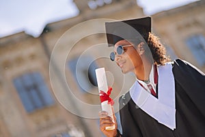 Bemused graduand standing in front of his university.